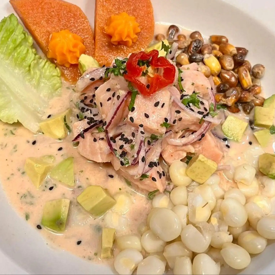 Peruvian ceviche with salmon, avocado, corn, sweet potato, and red pepper in a creamy sauce.